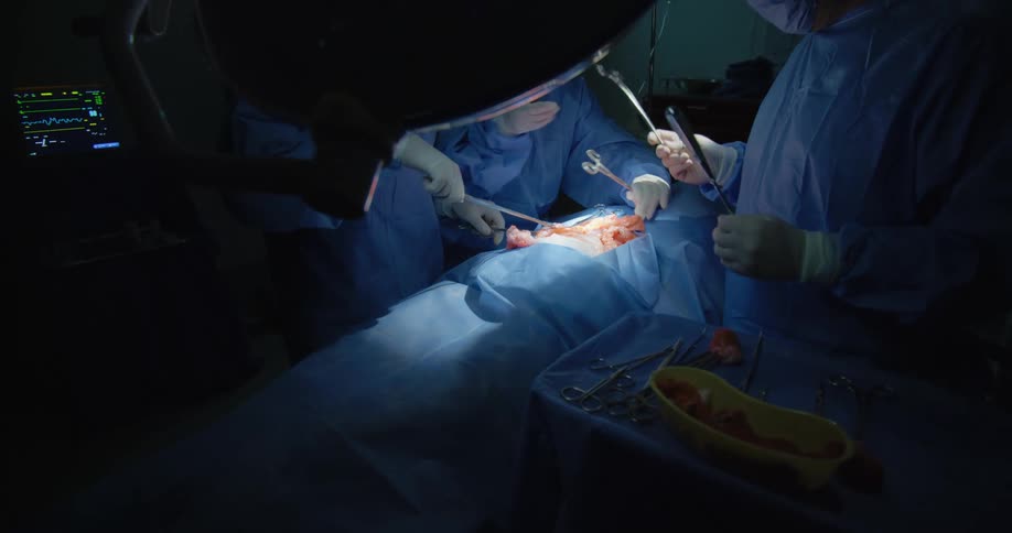 Medical team of three people performing surgery on a patient
