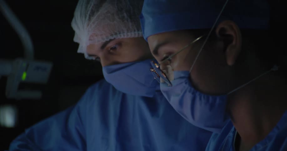 Close up of two surgeons standing in an operating theatre while performing a surgery