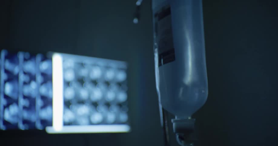 Serum bag hanging on a metal rod and in the background a screen displaying a scanner