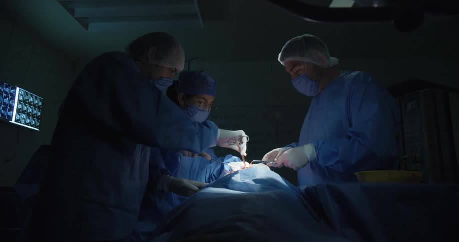 Three doctors operate on a patient in the operating theater