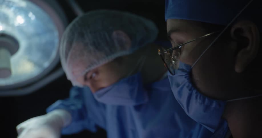 Man and woman in masks concentrating on a surgical procedure
