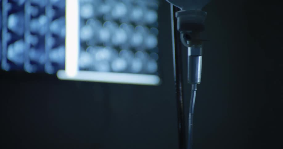 Close up of a drip chamber connected to a hanging drip bag in an operating theatre