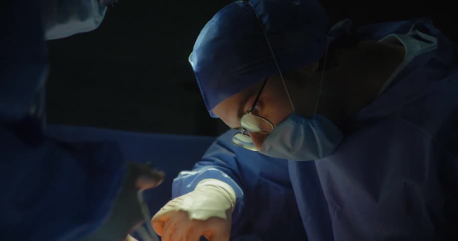 Woman concentrating on performing a surgical procedure on a patient accompanied by another professional