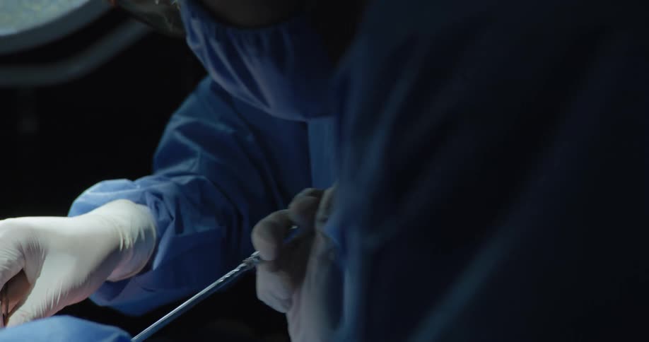 Two surgeons with scalpels concentrating on an operation