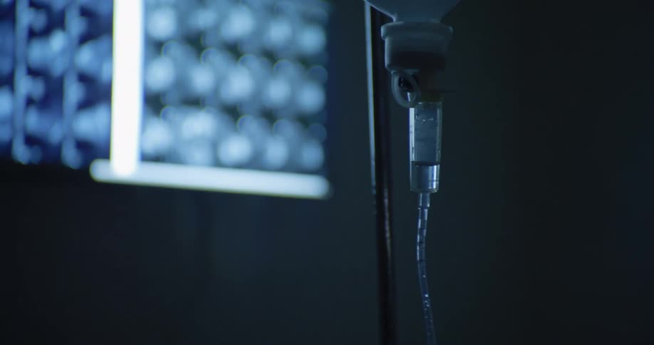 In a hospital a medical professional sets up an iv line attached to a long metal pole