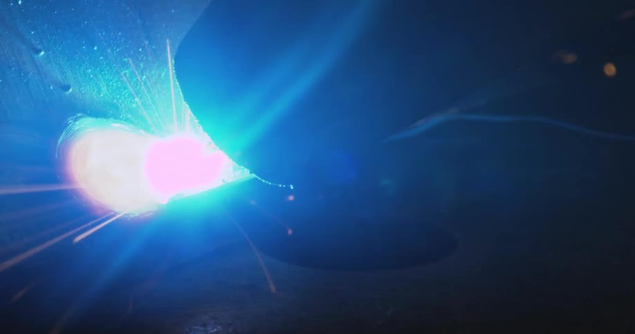 Machine performing welding on a metal surface with sparks