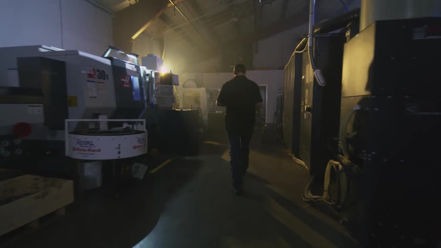 A man walks through a large warehouse filled with machinery