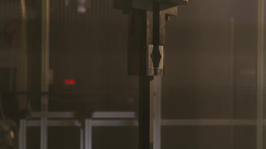 A robotic arm hovers above a row of uniformly arranged metal components in a dim industrial setting