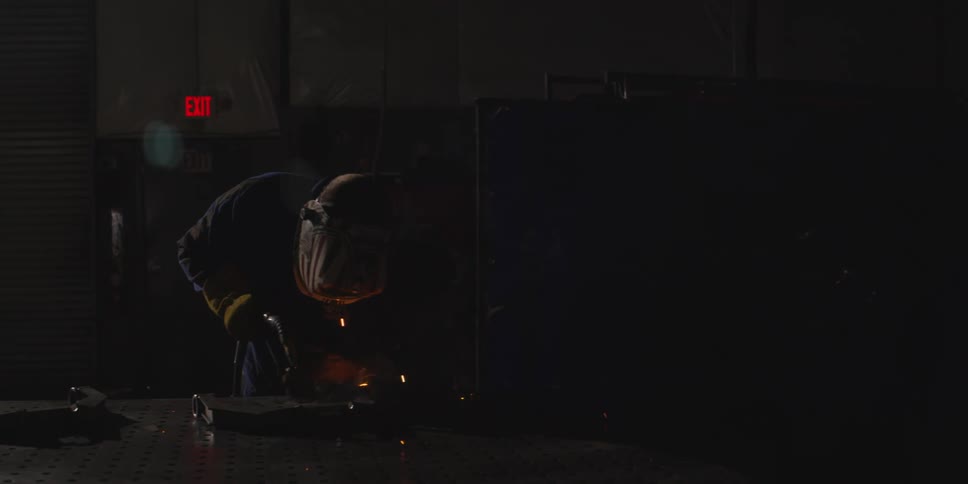 Person wearing a mask using a welding tool and emitting sparks