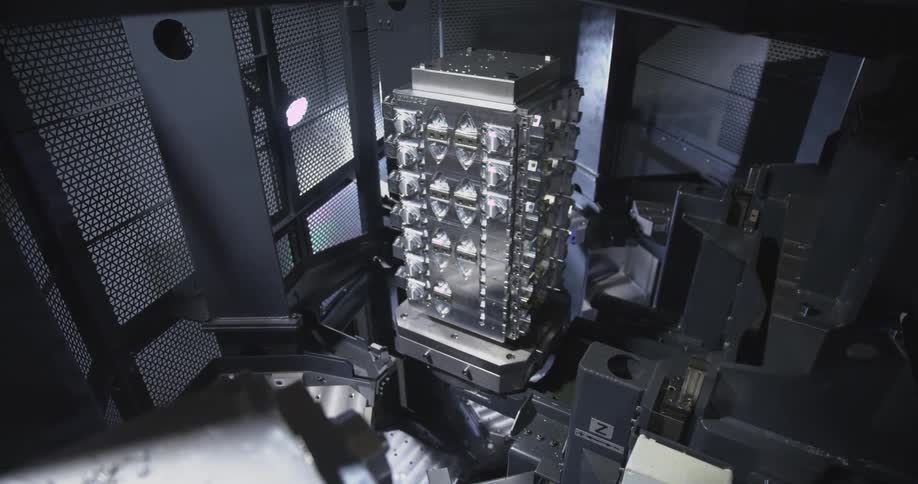 A highprecision industrial machine is positioned around a multisided metal fixture likely part of an automated cnc milling or manufacturing process inside a technologically advanced facility