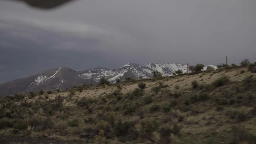 View of a snowy mountain from within a vehicle while traveling along the highway