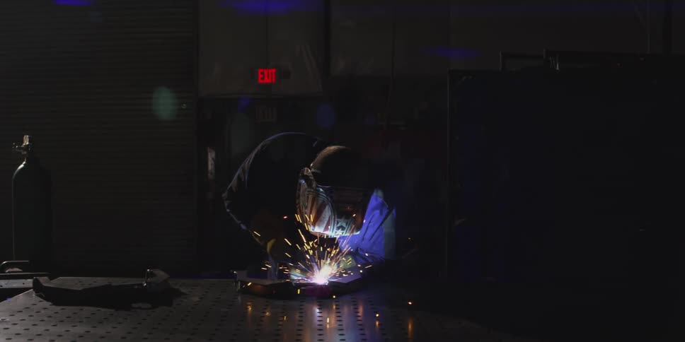 Person with protective helmet welding an object and sparks being emitted