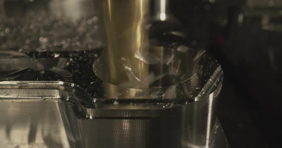 Golden machining tool performing high speed cutting on metal workpiece with flying particles