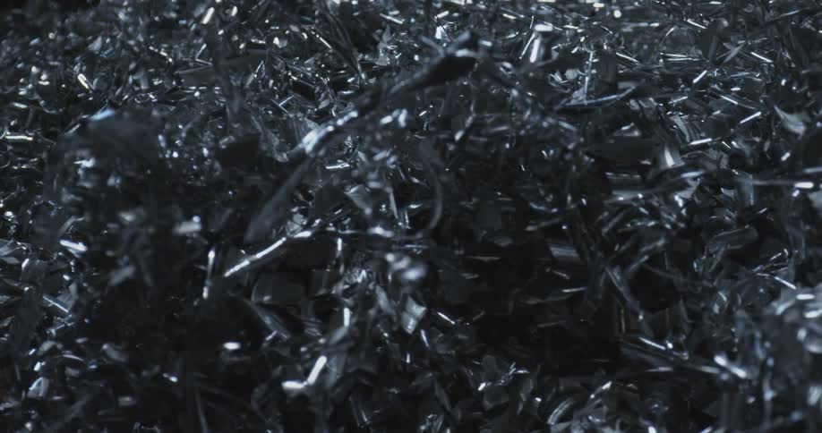 A tangled mass of shiny metallic shavings is tightly packed together reflecting light in various sharp chaotic patterns