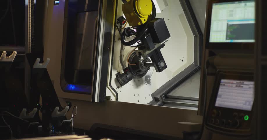Industrial robotic arm operating inside an automated control cabin with monitors around it