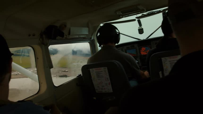 A small group of people sits in a plane as it takes off