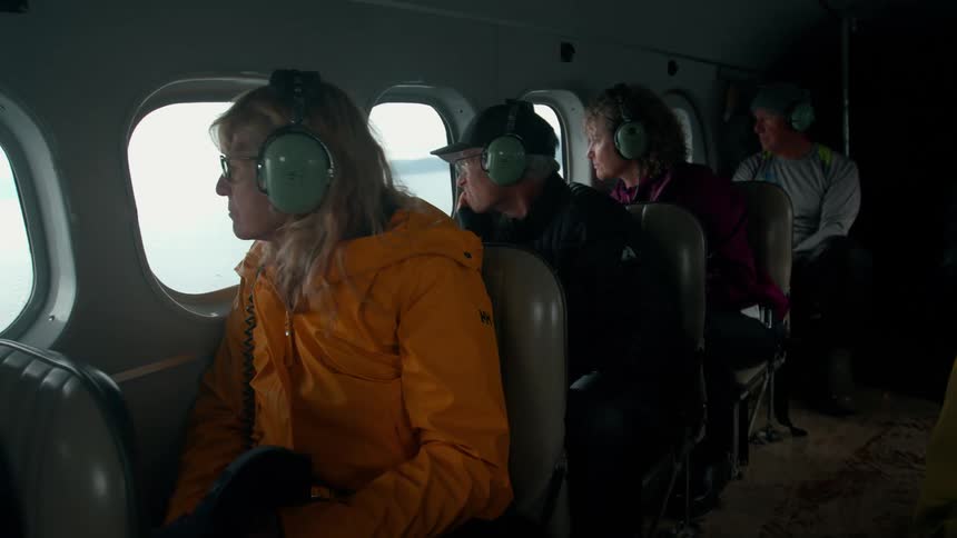 The travelers look out the window of the flying plane