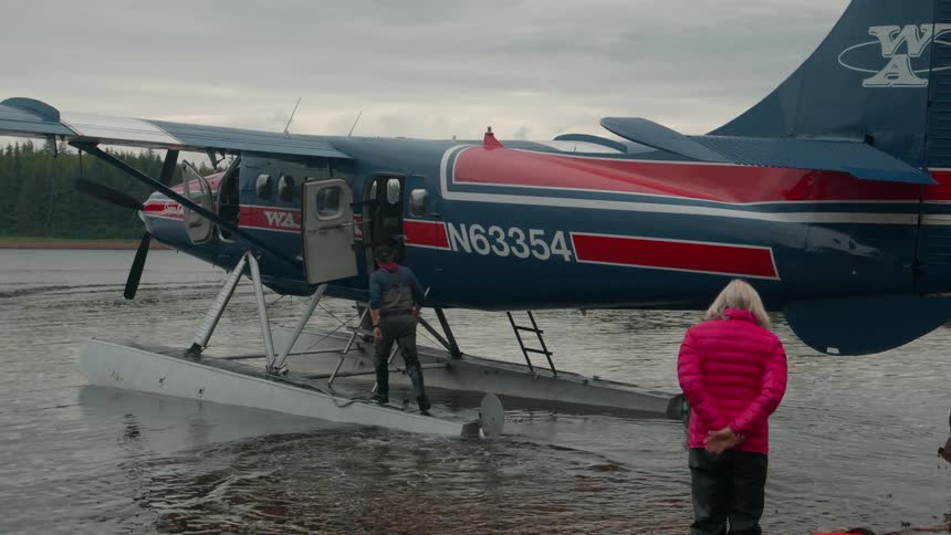 Travelers near a water plane parked on a lake