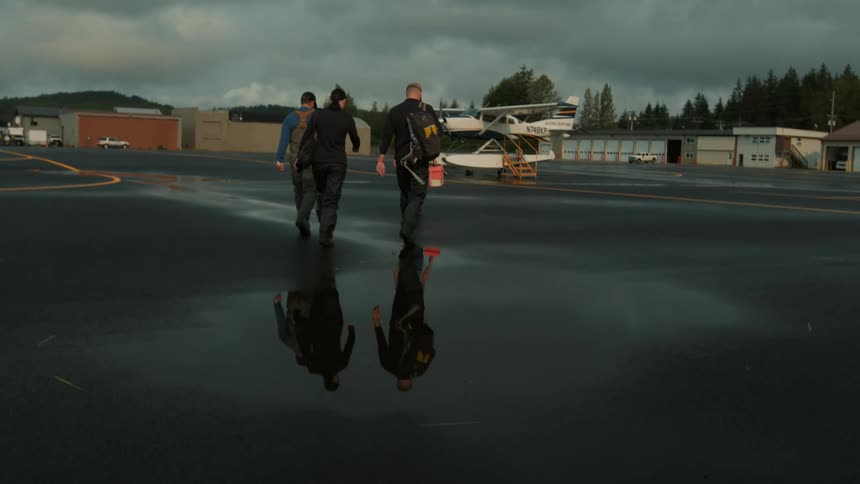Three people walk towards the plane on the runway