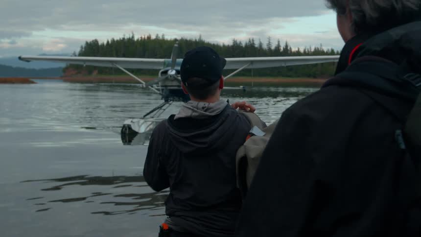 Two men with backpacks waiting in front of them for a water plane