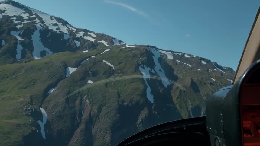 The helicopter flies high above the mountain