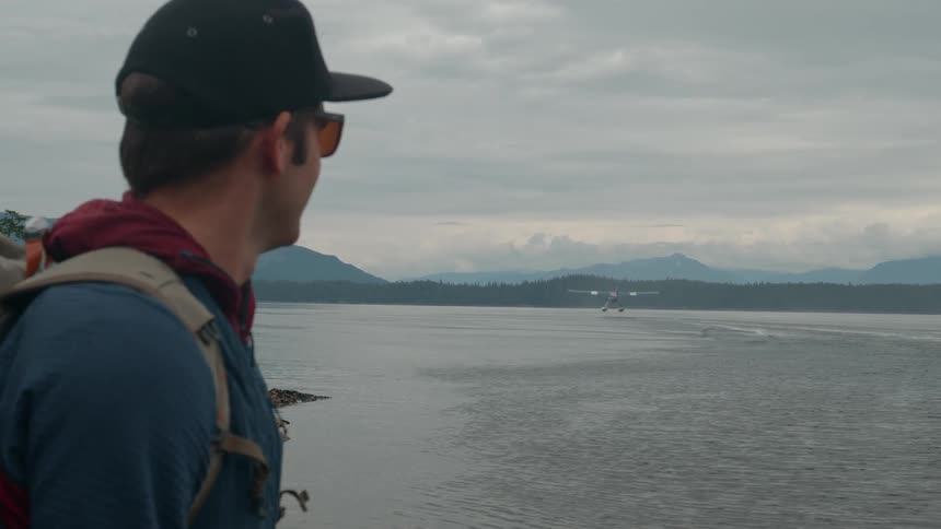Man in glasses and cap watching the sea with a water plane