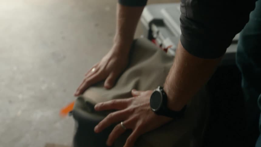 A closeup shows a person gently placing their hands on a dogs head wearing a black watch and wedding ring