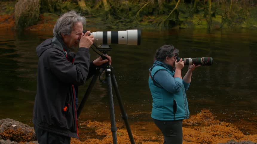 Man and woman professional photographers in a natural setting on the edge of a river