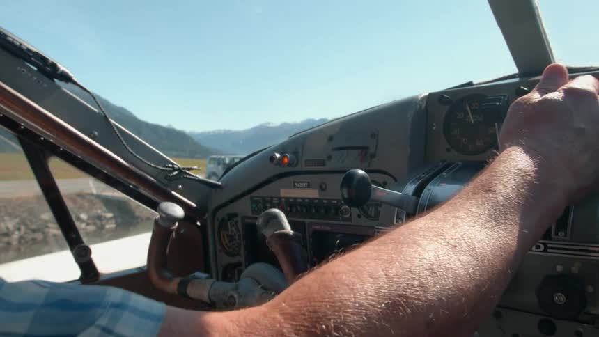 Close up of a male pilot manipulating controls at the cockpit of an aircraft while in the air