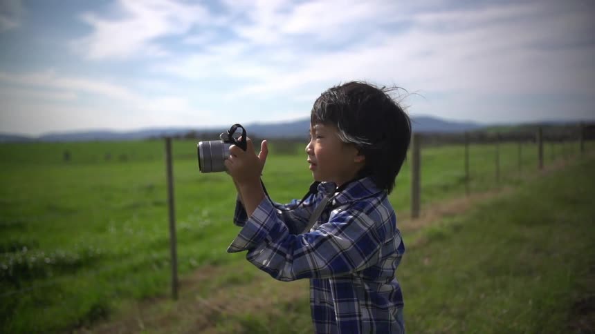 A boy takes a photograph outside