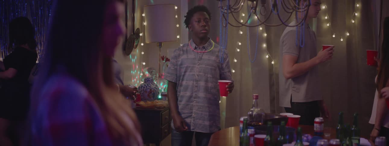 A young boy dances at a party while holding a red cup