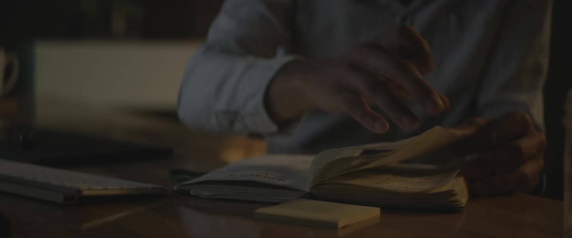 A man in a blue shirt flips through a book