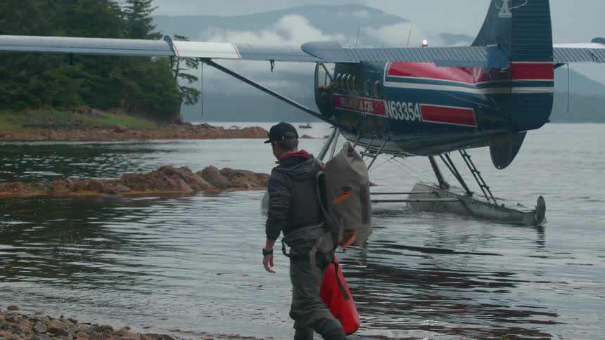 Man with backpacks walking towards a water plane on a lake