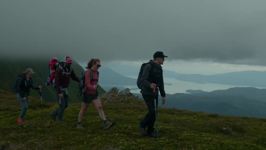 Group of four people hike together on a cloudy day
