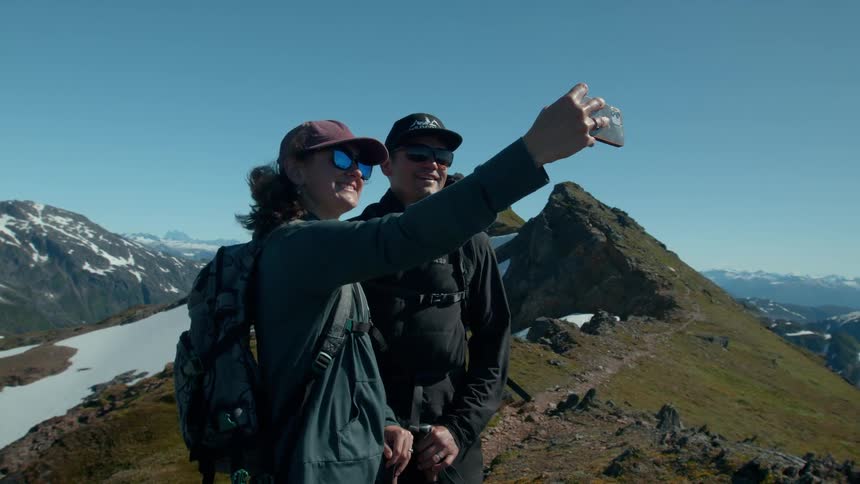 A couple take a selfie on the windy mountain