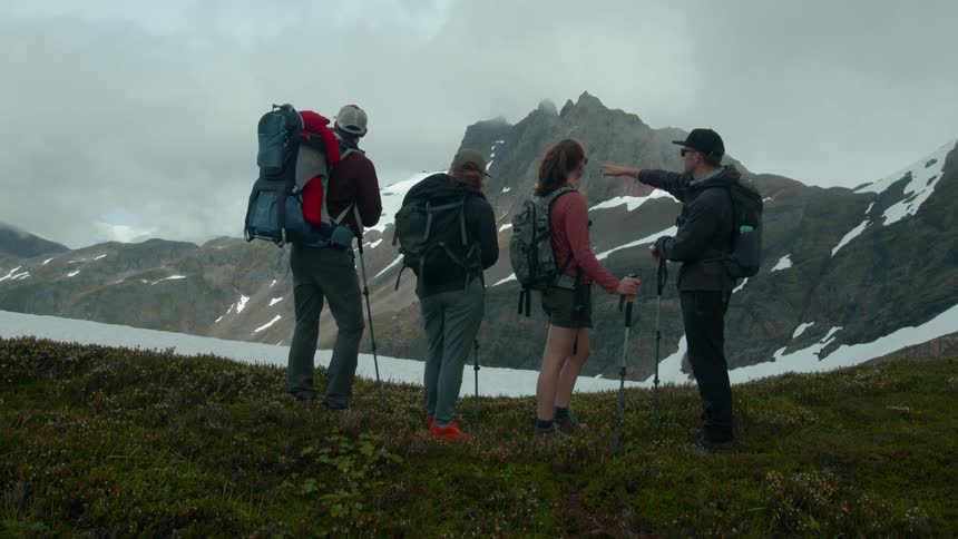 A group of hikers stop to discuss their route on a mountain trail