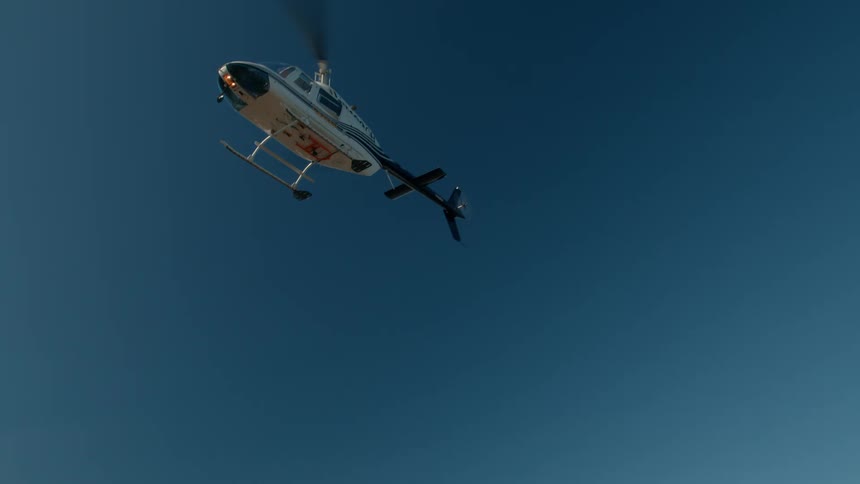 The helicopter takes off and flies over the mountains