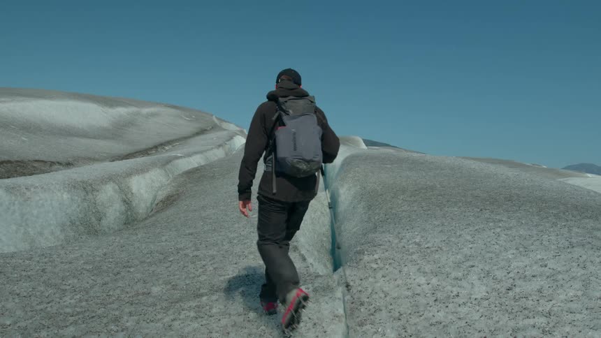 The hiker stops to look in the crevice of the ice