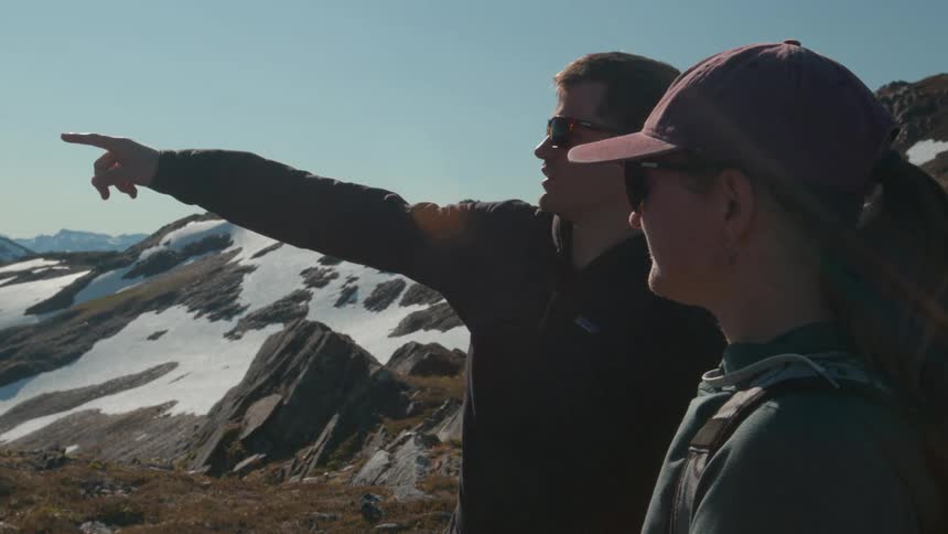 A man points at the mountains while talking with a woman