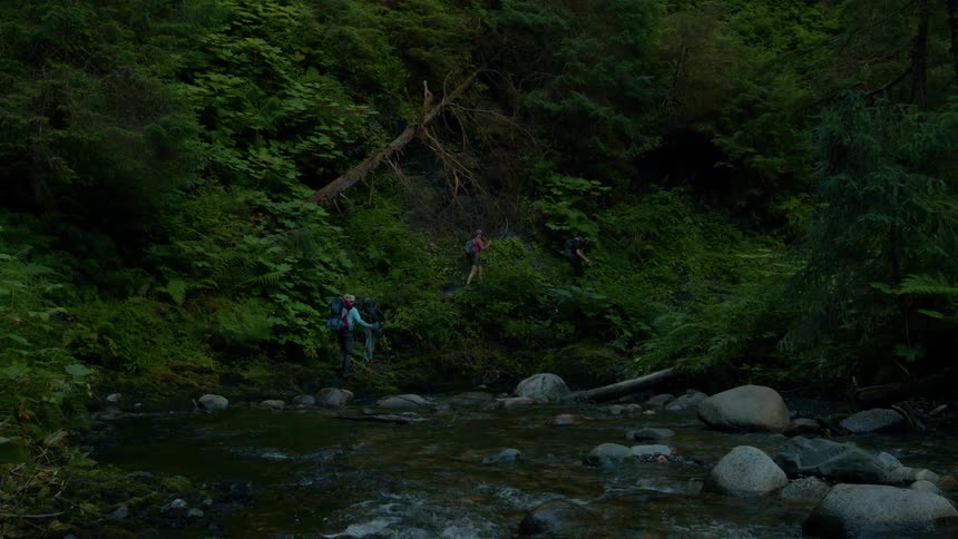 Group of people crossing a river on a mountain trail