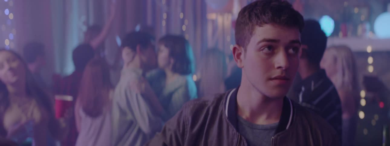 A young man walks through a party with flashing lights