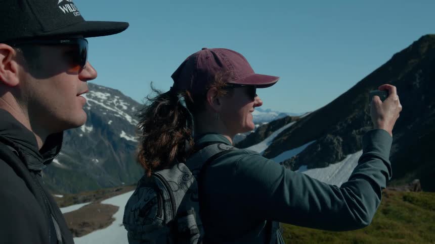 Tourist records the mountain scenery with a phone while hiking