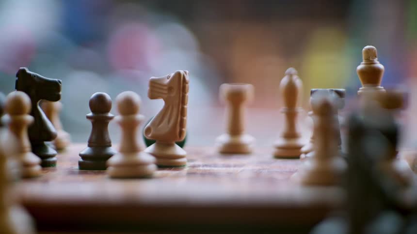 Close up of a person winning a chess game with their knight on a chess board outdoors during daytime