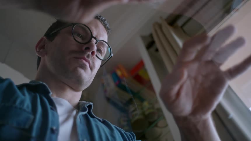 The man is tapping his fingers on the glass
