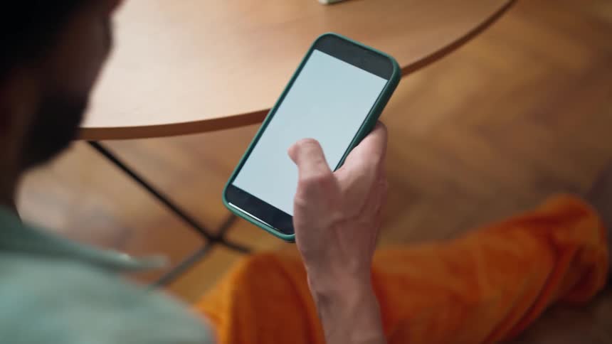 Seated man interacting with a smartphone