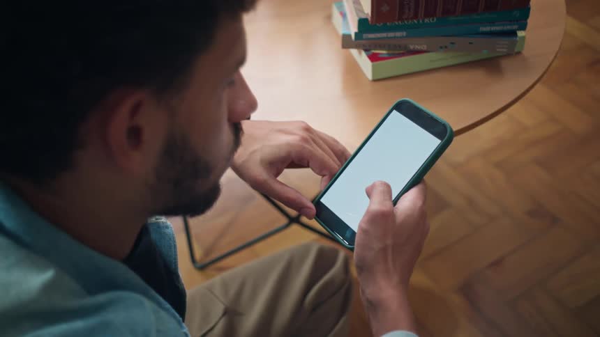 A man sitting in the dining room while looking at his phone