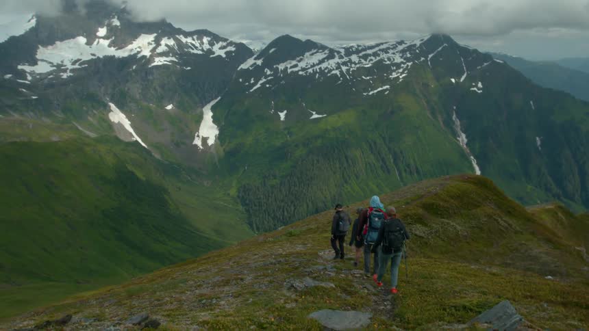 A group of four people are hiking through the mountains