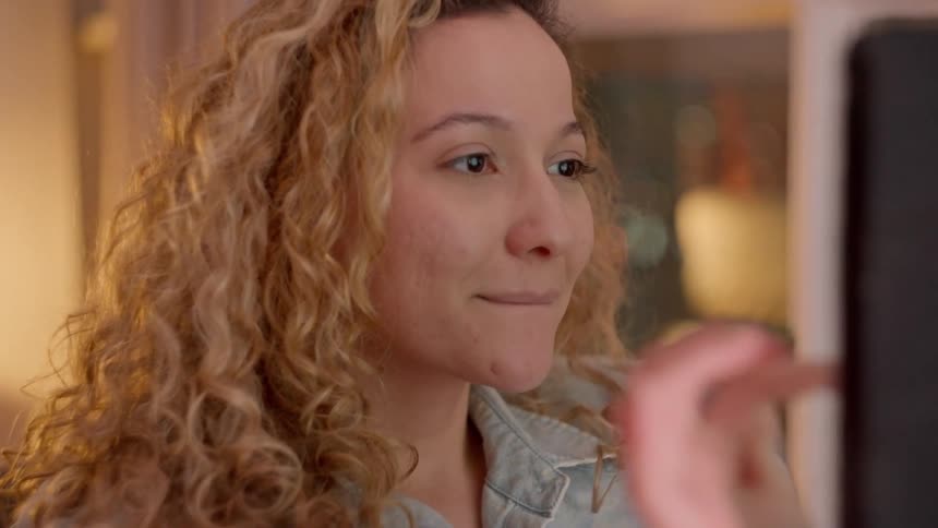 Blonde woman with curly hair interacting with an electronic device