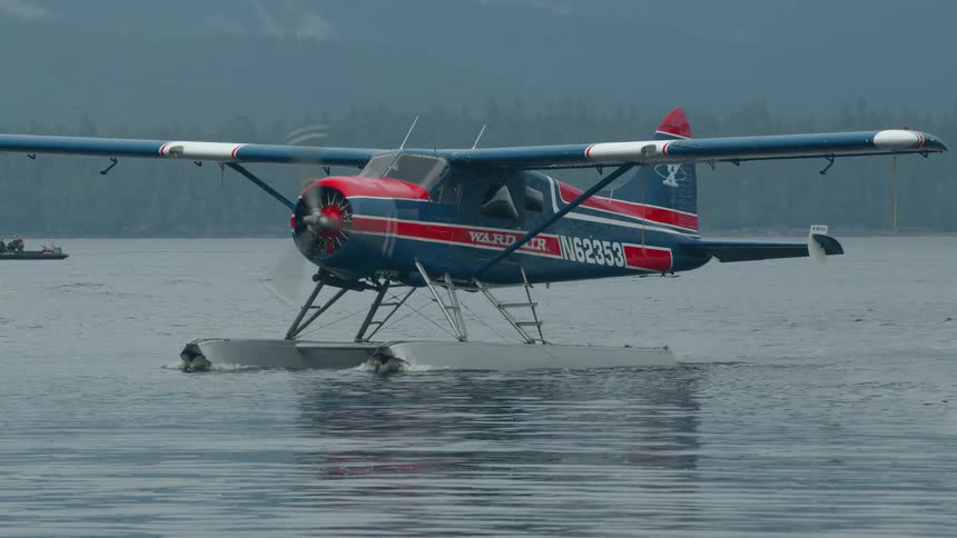 A classic red and blue floatplane also known as a seaplane resting on the surface of calm water the plane has large floats instead of wheels allowing it to land and take off from water bodies the visible registration number on its side is n62353