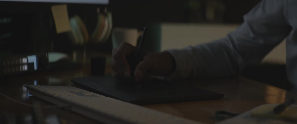 A man sits at a computer while studying a notebook